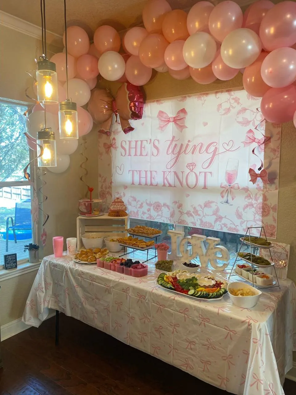 Buffet table in front of a pink bridal shower backdrop, set up by Oak & Lace