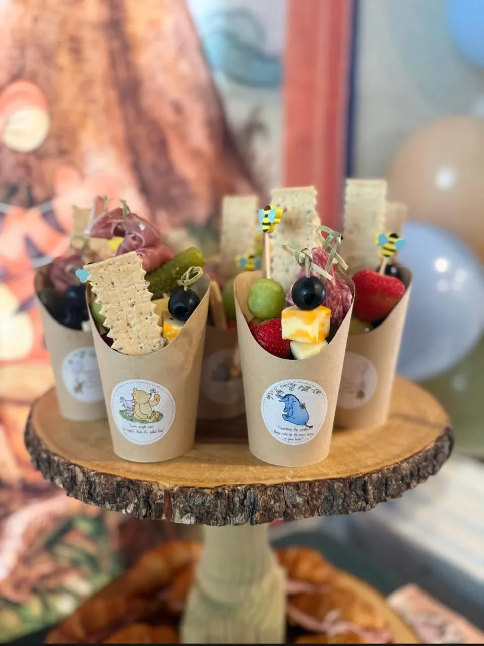 Fruit and cracker cups on a wooden slice stand with woodland labels